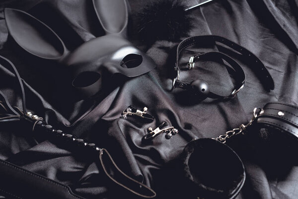 rabbit mask near sex toys on black silk fabric 