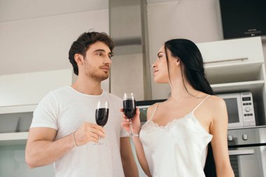 Evde yalnızlık çekerken kırmızı şarap bardaklı güzel bir çift. 