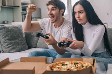 KYIV, UKRAINE - 16 Nisan 2020: heyecanlı bir çift evde izolasyon sırasında oyun oynuyorlar ve pizza yiyorlar. 