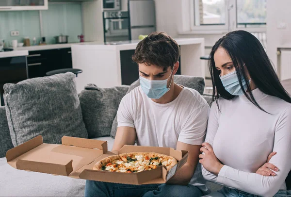 Pareja Enferma Máscaras Médicas Mirando Pizza Casa Durante Auto Aislamiento —  Fotos de Stock