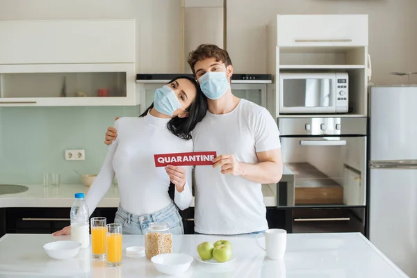 Pareja Máscaras Médicas Desayunando Sosteniendo Signo Cuarentena Casa Durante Autoaislamiento — Foto de Stock