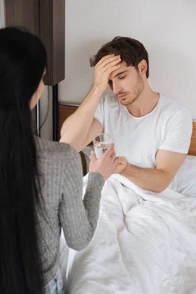 Mujer Dando Vaso Agua Hombre Cansado Con Dolor Cabeza Cama — Foto de Stock