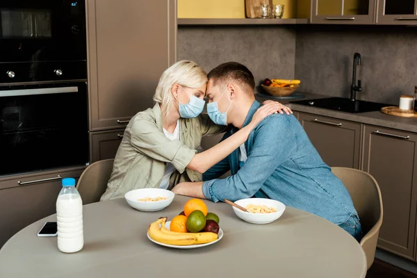 Pareja Máscaras Médicas Abrazándose Mientras Desayuna Cocina —  Fotos de Stock