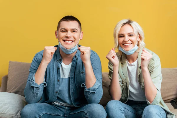 Fröhliches Paar Medizinischen Masken Zeigt Gesten Auf Sofa Nahe Gelber — Stockfoto