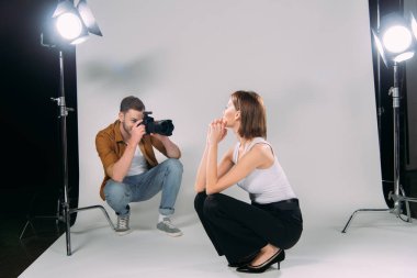 Fotoğraf stüdyosunda çekici bir modelin fotoğrafını çeken bir fotoğrafçı. 