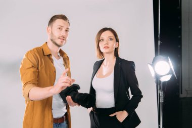 Yakışıklı fotoğrafçı, fotoğraf stüdyosunda güzel bir modelin yanında parmağını gösterdi. 