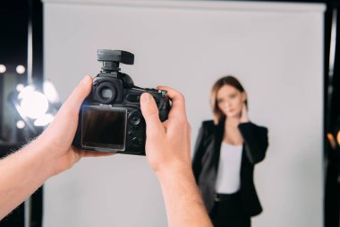 Fotoğraf stüdyosunda fotoğrafçının fotoğraf makinesini modelin yanında tuttuğu seçici odak noktası 