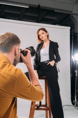 Fotoğraf stüdyosundaki sandalyede poz veren zarif modelin seçici odağı. 