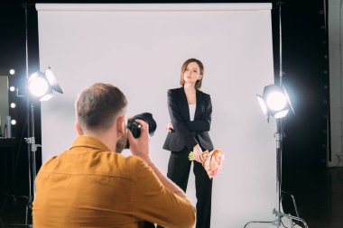 Fotoğraf stüdyosunda fotoğraf makinesiyle fotoğrafçıya poz veren şık modelin seçici odağı 