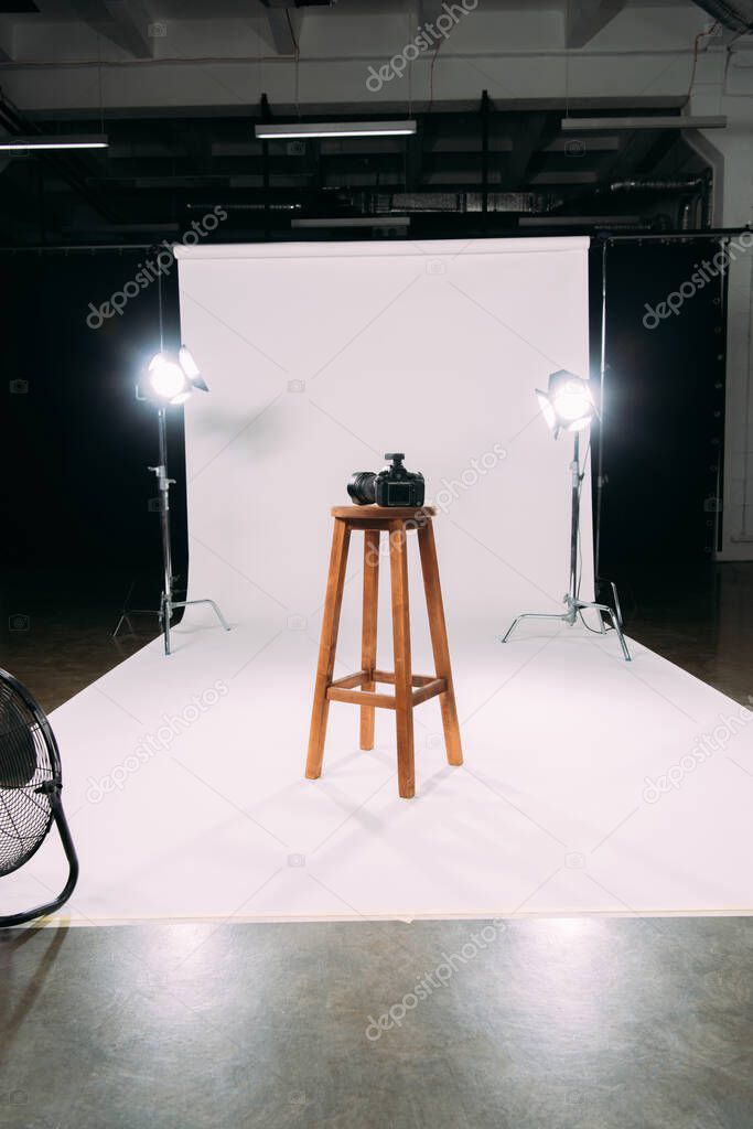 Digital camera on wooden chair in photo studio 
