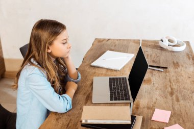 Evde ders çalışırken boş ekranla dizüstü bilgisayara bakan çocuğun yan görüntüsü 