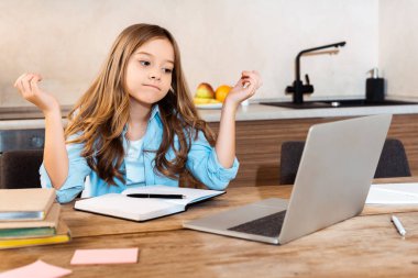 Evde e-öğrenim görürken dizüstü bilgisayara bakan kafası karışık çocuğun seçici odağı