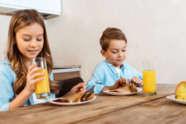 Enfoque Selectivo Hermana Feliz Sosteniendo Vaso Jugo Naranja Cerca Hermano —  Fotos de Stock