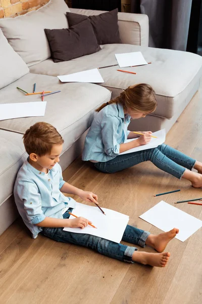 かわいいお兄さんとお姉ちゃんが床に座ってリビングで絵を描く — ストック写真