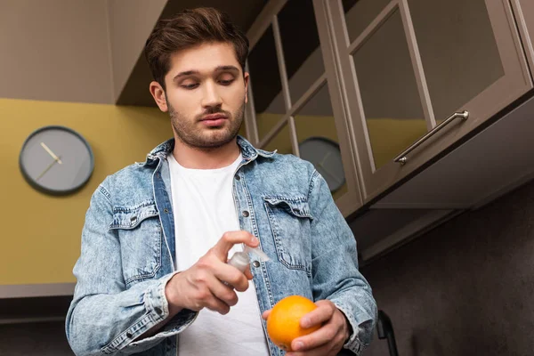 Vista Ángulo Bajo Del Hombre Guapo Usando Antiséptico Sosteniendo Naranja —  Fotos de Stock