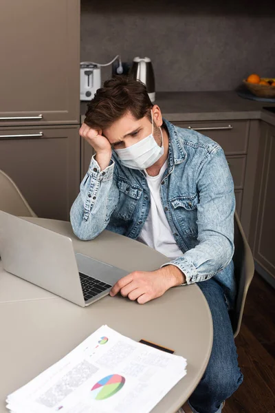 Telelavoro Sconvolto Maschera Medica Guardando Computer Portatile Vicino Carte Con — Foto Stock