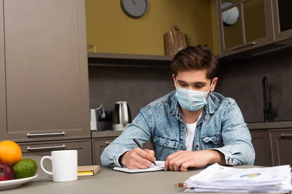 Focus Selettivo Dell Uomo Maschera Medica Scrittura Notebook Sul Tavolo — Foto Stock