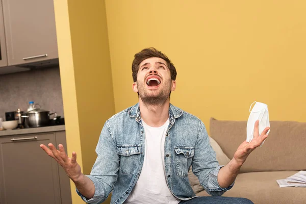 Wütender Mann Mit Medizinischer Maske Und Blick Auf Couch Hause — Stockfoto