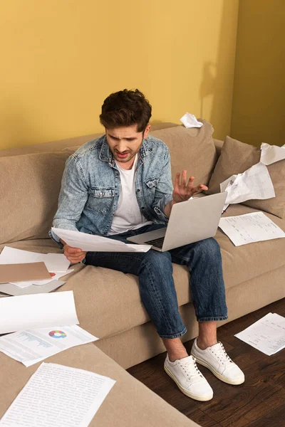 Displeased Man Holding Document While Working Laptop Couch Living Room — Stock Photo, Image