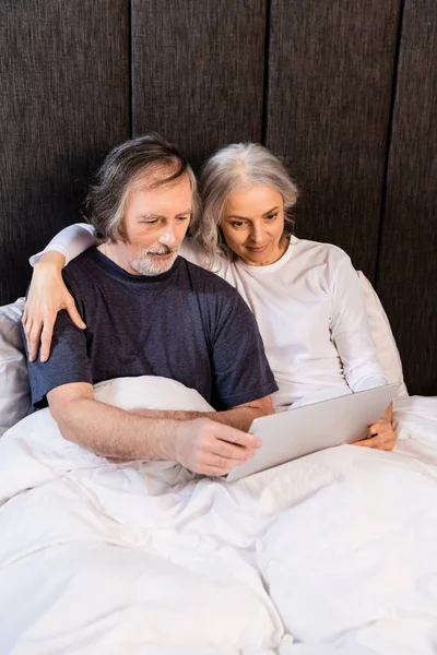 Pareja Madura Mirando Portátil Dormitorio —  Fotos de Stock