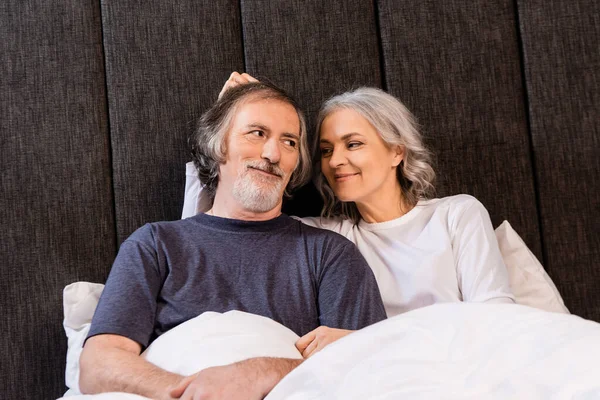 Happy Mature Woman Touching Hair Husband Smiling Bed — Stock Photo, Image