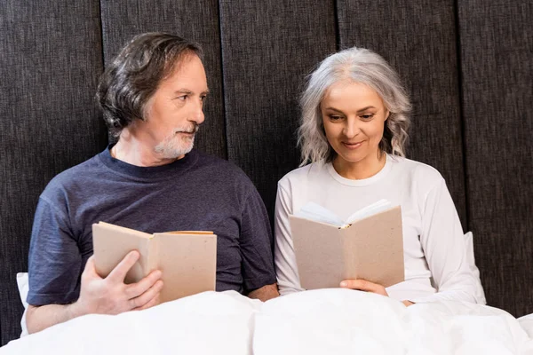 Bearded Mature Man Looking Happy Wife Reading Book Bed — Stock Photo, Image