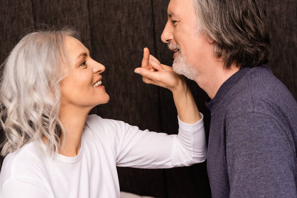 side view of happy mature woman pointing with finger at husband