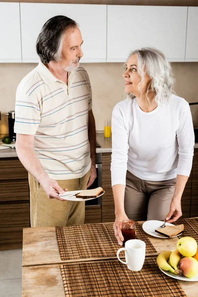 Mujer Madura Feliz Mirando Marido Tocando Frasco Con Mermelada — Foto de Stock