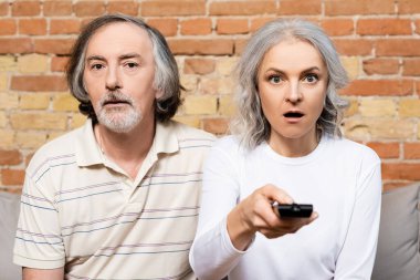 Oturma odasında film izleyen, şaşırmış ve olgun çiftlerin seçici odağı. 