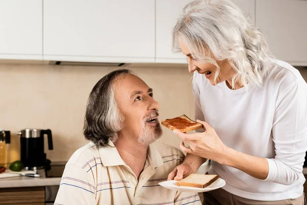 Happy Mature Woman Feeding Husband Sweet Toast Bread — Stock Photo, Image