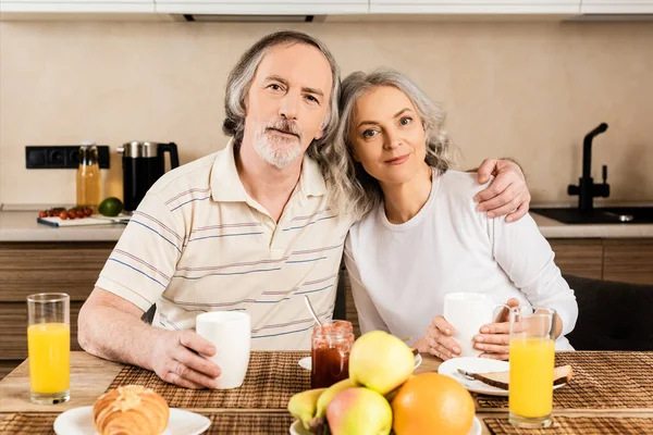 Glada Mogna Par Tittar Kameran Nära Frukost Bordet — Stockfoto