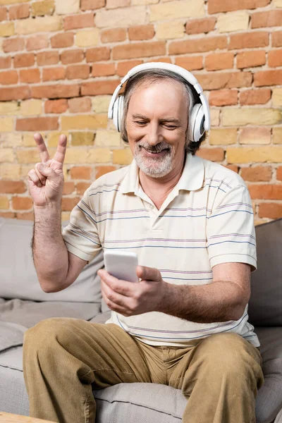 Hombre Feliz Maduro Auriculares Inalámbricos Tomando Selfie Mostrando Signo Paz — Foto de Stock