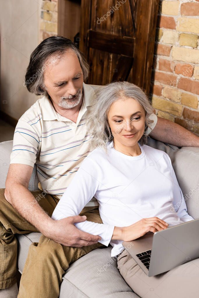 happy and mature freelancers using laptop at home 