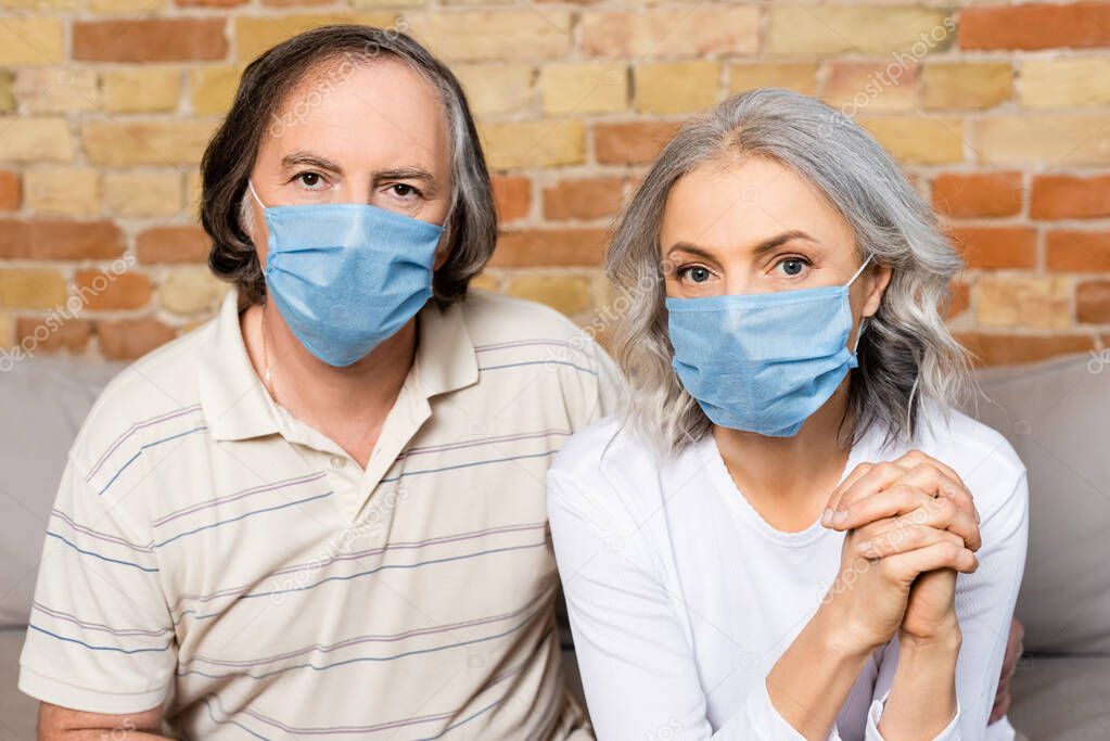 mature couple in medical masks looking at camera  