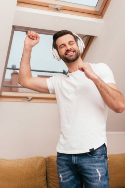 Evde kulaklıkla müzik dinlerken neşeli adam dans ediyor. 