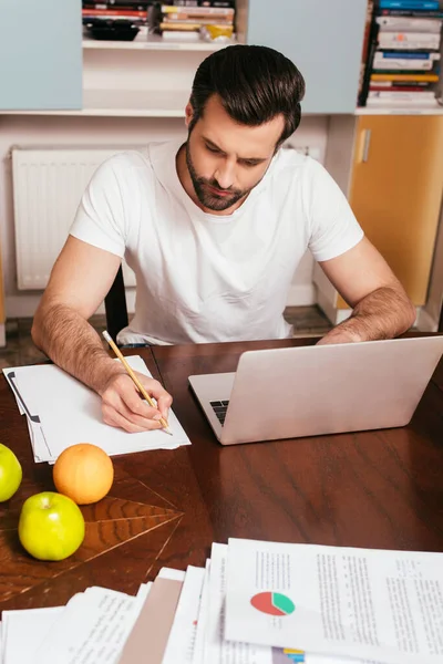 Enfoque Selectivo Del Apuesto Freelancer Usando Laptop Escribiendo Papel Cerca — Foto de Stock