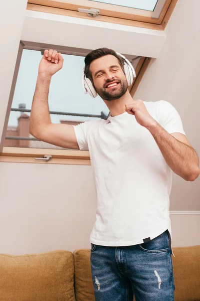 快乐的男人一边在家里用耳机听音乐一边跳舞 — 图库照片