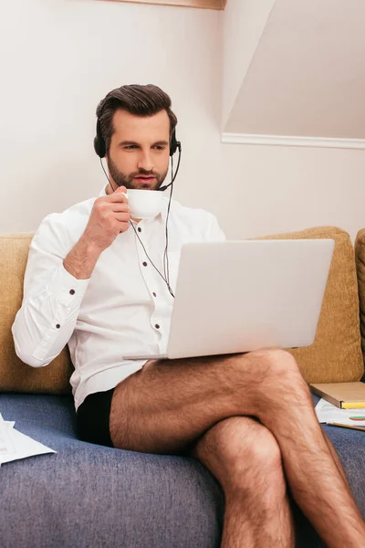 Handsome Freelancer Shirt Panties Drinking Coffee Using Headset Laptop Couch — Stock Photo, Image