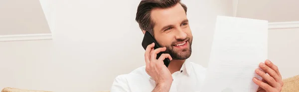 Akıllı Telefonla Konuşurken Gülümseyen Belgeyi Evde Tutan Yakışıklı Bir Tele — Stok fotoğraf