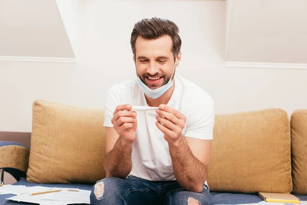 Cheerful Man Medical Mask Holding Thermometer Papers Couch — Stock Photo, Image
