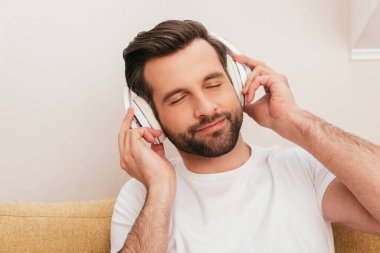 Evde kulaklıkla müzik dinleyen, gözleri kapalı yakışıklı adam. 