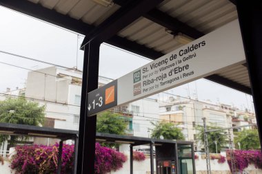 Nameplate with pointers on train station in Catalonia, Spain clipart