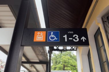 Signs and symbols on nameplate of train station in Catalonia, Spain  clipart
