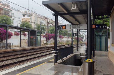 Katalonya, İspanya 'da çiçek açan çalıları ve isim levhaları olan tren istasyonu