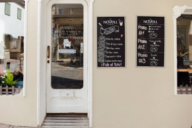 CATALONIA, SPAIN - 30 Nisan 2020: Kafe kapısının yanındaki duvarda menü bulunan isim plakaları