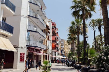 CATALONIA, SPAIN - 30 Nisan 2020: Şehir caddesinde palmiye ağaçları ve açık hava kafesi olan insanlar 