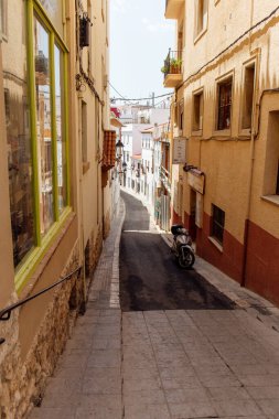 Scooter near buildings on walkway of urban street in Catalonia, Spain  clipart