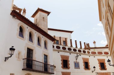 Low angle view of street lanterns on facades of buildings with blue sky at background in Catalonia, Spain  clipart