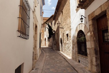 Street lanterns and sunlight on facades of buildings on urban street in Catalonia, Spain  clipart