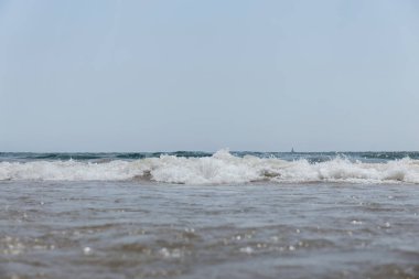 Selective focus of sea with waves and blue sky at background in Catalonia, Spain  clipart